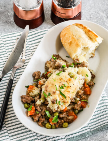 Air fryer cottage pie serving on an oval plate with crusty bread.