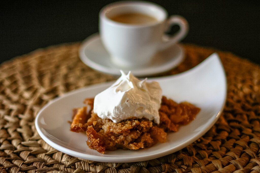 a dessert dish with apple brown betty and a dollop of whipped cream