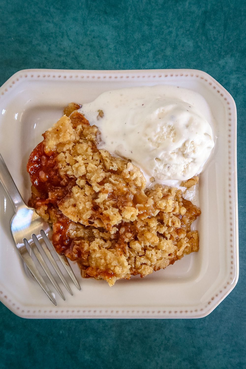 a serving of apple crisp on a plate with ice cream