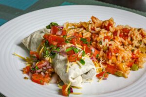 beef and bean burritos on a plate with mexican rice and salsa