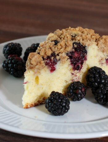 blackberry crumb cake on a plate with fresh blackberries