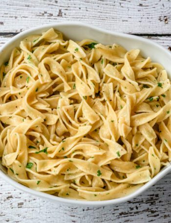 buttered noodles with parsley in a serving bowl