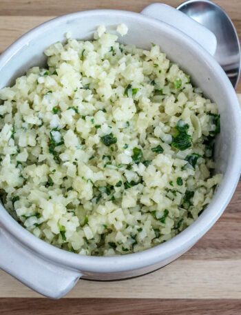 A bowl of cauliflower rice with garlic, parmesan cheese, and parsley