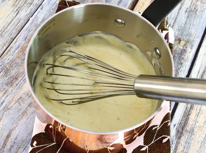 cheese sauce in a copper pan with whisk