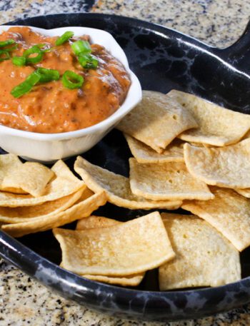 chili cheese dip with sausage on a plate with chips