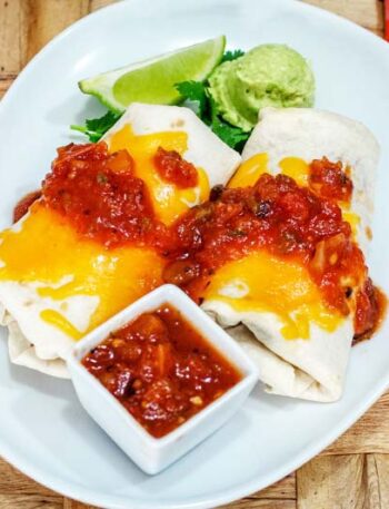 chicken burritos on a plate with salsa and guac