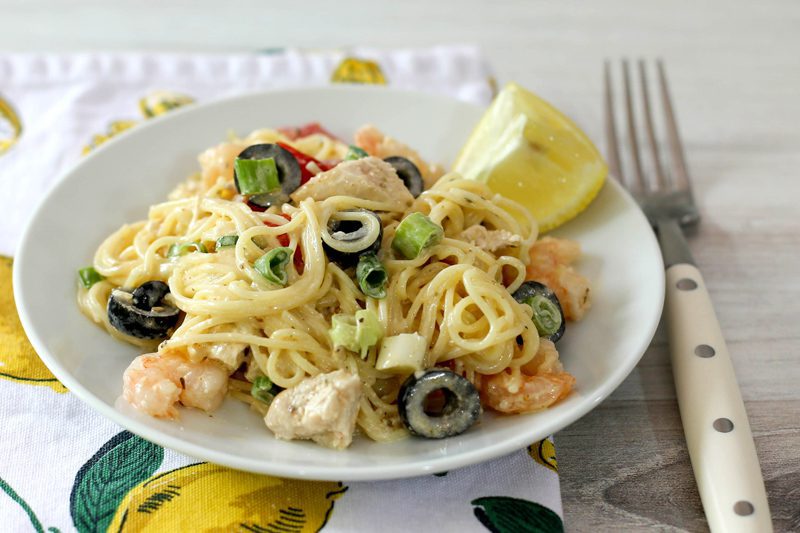 serving of chicken and shrimp pasta salad with angel hair pasta, lemon, olives, and green onions