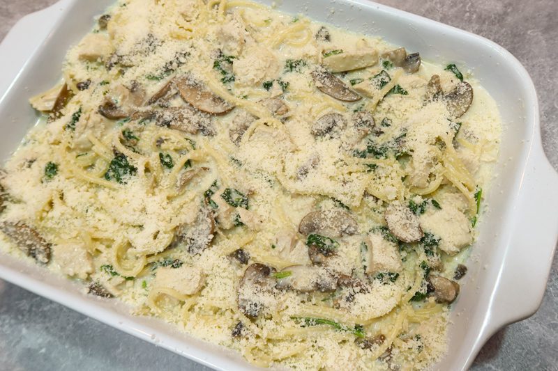 Baking dish with chicken tetrazzini ready to bake with a topping of parmesan cheese