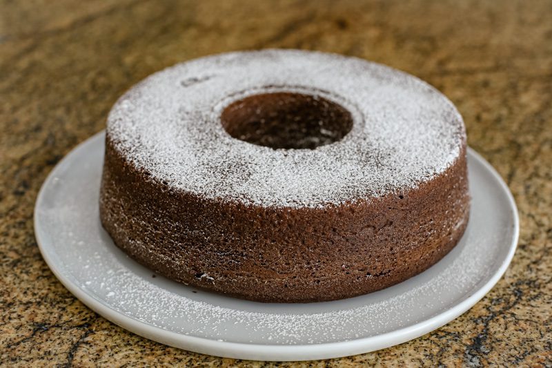 chocolate sponge cake on a plate, dusted with powdered sugar