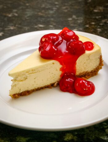 A slice of classic cheesecake with a garnish of cherry pie filling