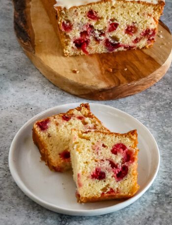 slices of cranberry orange bread on a plate with the loaf in the background