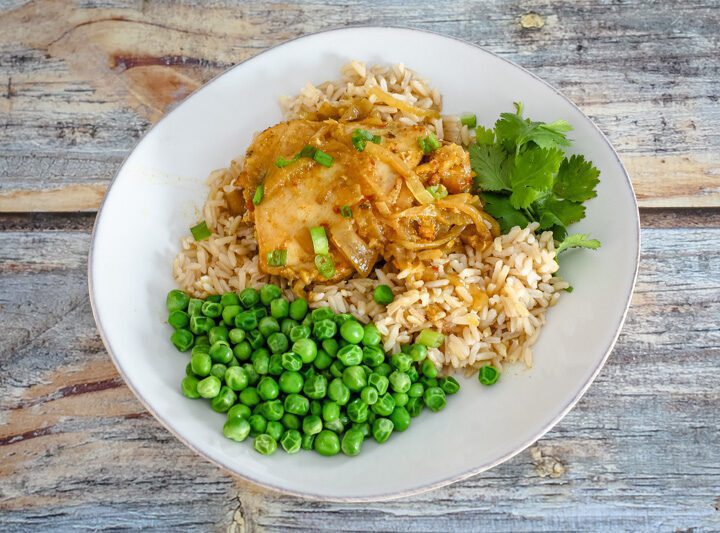 slow cooker chicken with curry flavor on a plate with rice and peas