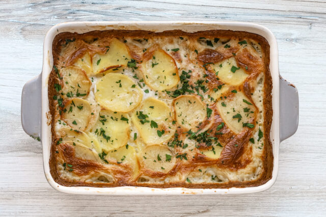 Dauphinoise potatoes are garnished with fresh parsley and ready to serve.