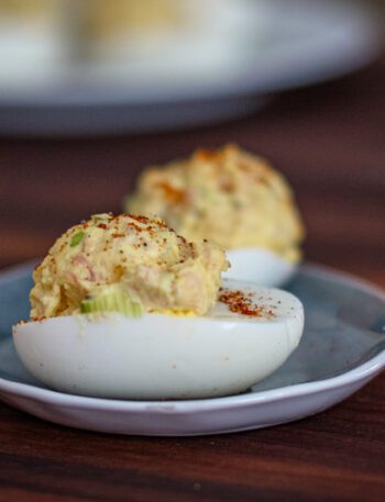 deviled eggs with ham on a small dish with more in the background