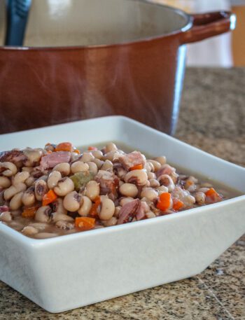 black-eyed peas in a serving dish with a dutch oven in the background
