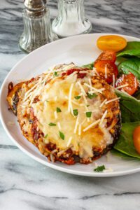 eggplant parmesan serving on a plate with salad