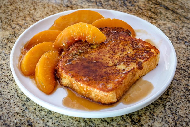 french toast on a plate with caramelized peaches