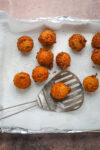 Freshly fried hush puppies from the fryer, draining on paper towels.