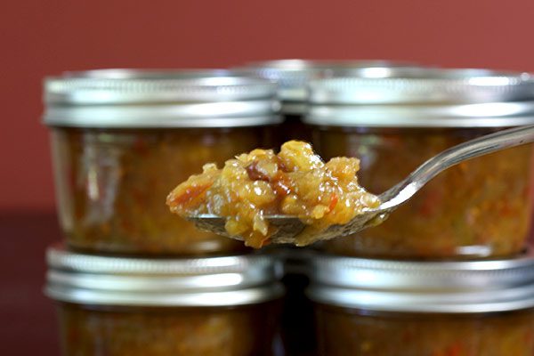 green tomato chutney in jars with spoon of chutney in foreground