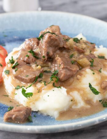 instant pot beef tips with mashed potatoes and fresh sliced tomatoes