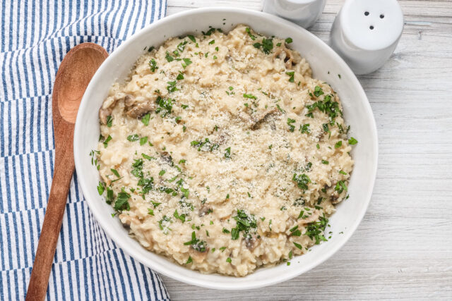 A bowl of Instant Pot mushroom risotto with a garnish of parsley and Parmesan cheese.
