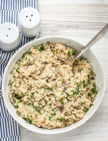 A bowl of Instant Pot mushroom risotto with a garnish of parsley and Parmesan cheese.