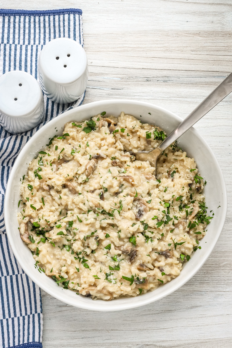 A bowl of Instant Pot mushroom risotto with a garnish of parsley and Parmesan cheese.