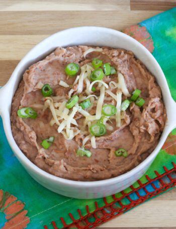 instant pot refried beans in a bowl with cheese and green onion garnish