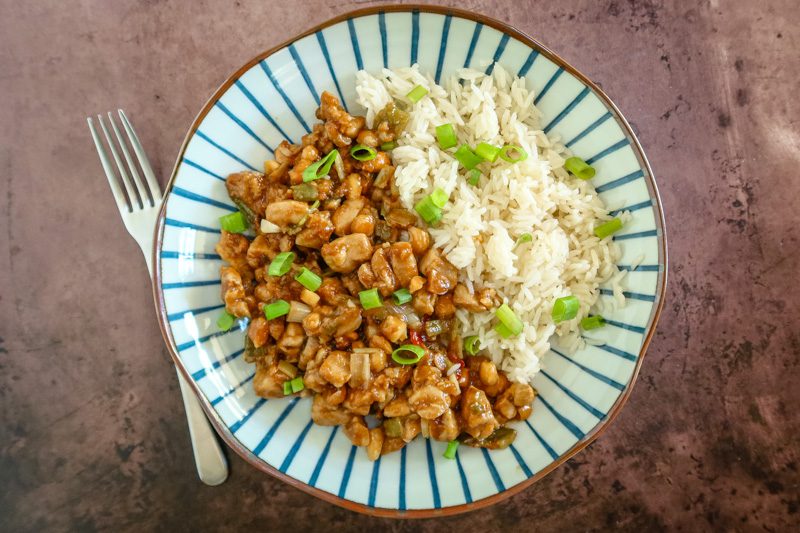 A plate of kung pao chicken with rice