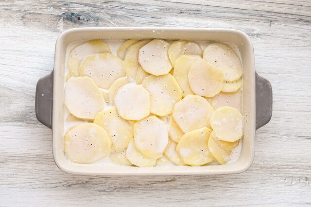 Layered potatoes and seasoned cream for dauphinoise potatoes.