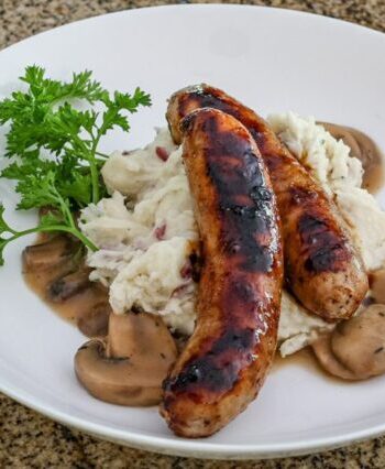Mushroom sauce with beef stock, garlic, and a splash of beer shown with mashed potatoes and grilled sausages.
