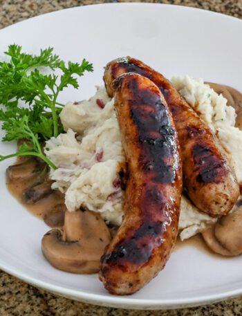Mushroom sauce with beef stock, garlic, and a splash of beer shown with mashed potatoes and grilled sausages.