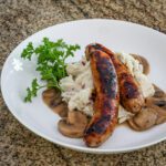 Mushroom sauce (ragout) shown with mashed potatoes and grilled sausages.
