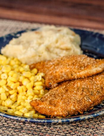 spiced oven fried chicken on a plate with potatoes and corn