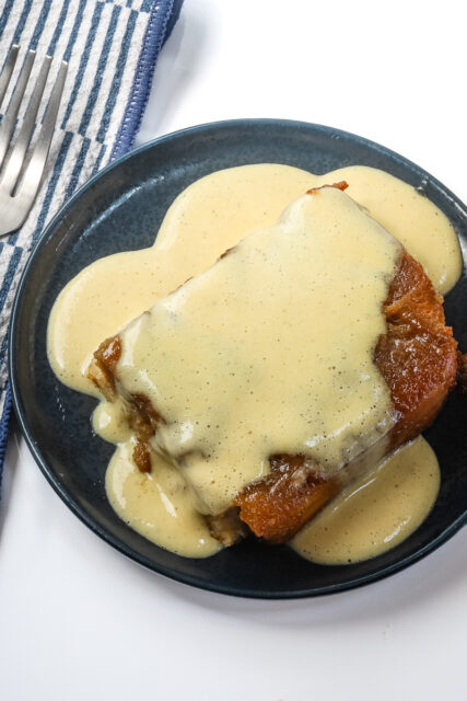 Overnight French toast served on a small plate with creme anglaise.