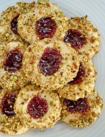 pistachio thumbprint cookies with jam center, arranged on a plate