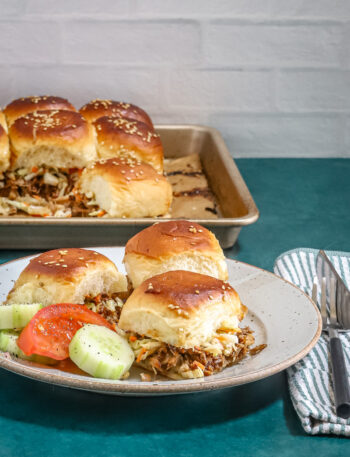 Pulled pork slider buns on a plate, baked and ready to enjoy.