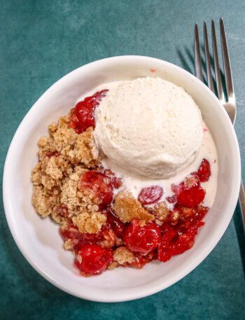an easy cherry crisp in a dessert dish with a scoop of ice cream