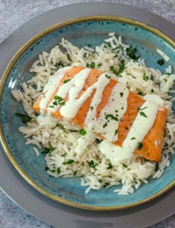 a salmon fillet on a bed of rice with a drizzle of basil mayonnaise.