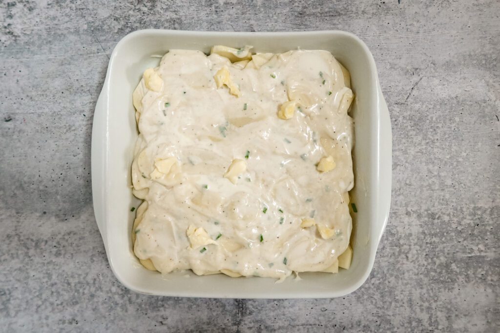 scalloped potatoes, preparation in the baking dish dotted with butter