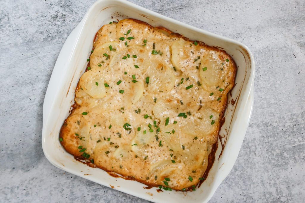 baked scalloped potatoes in the baking dish, garnished with chives