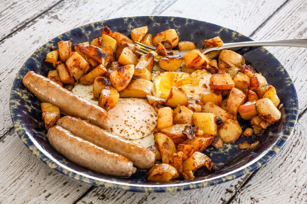 A plate of perfectly cooked home fries with sausages and eggs