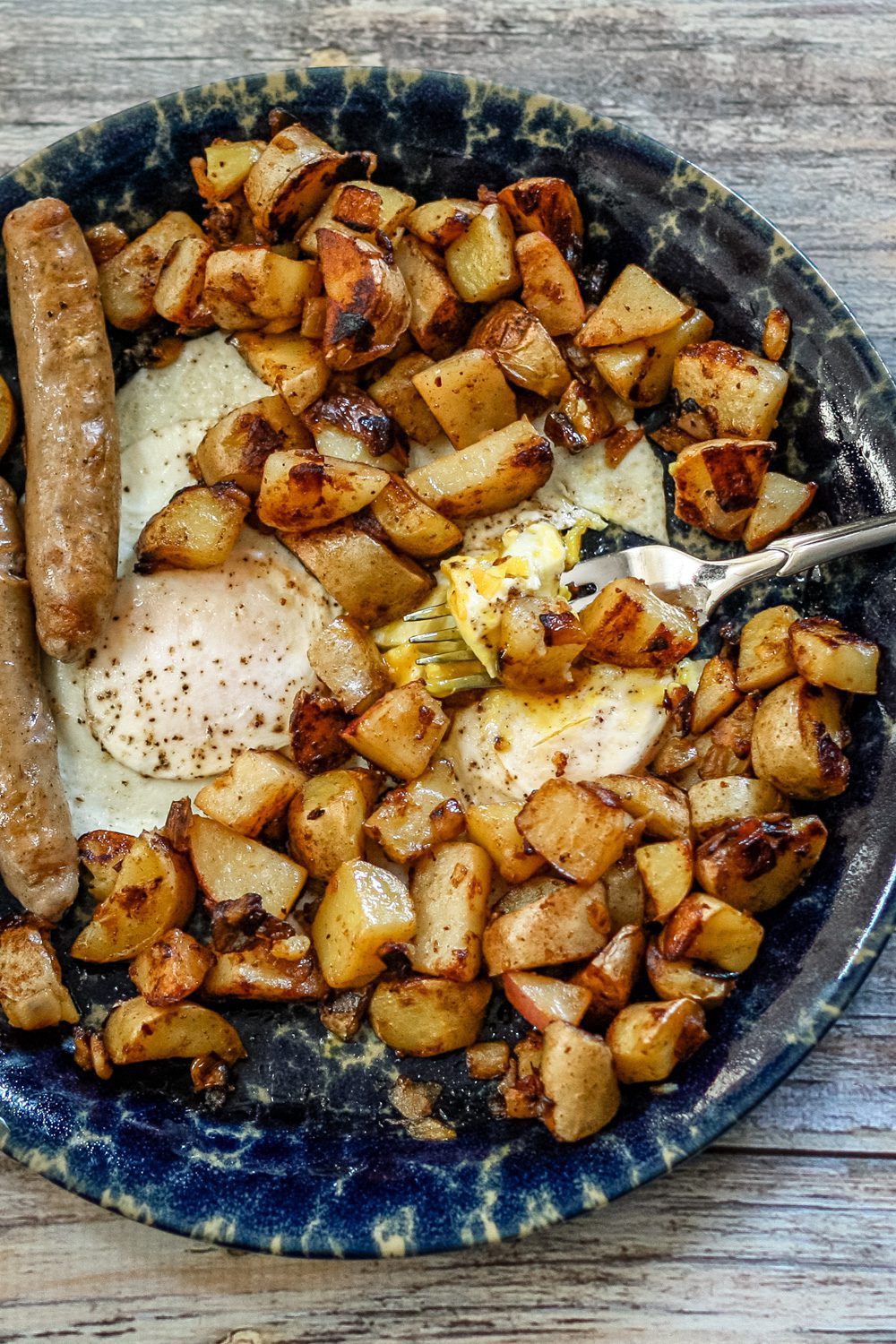 skillet home fries shown in a plate with eggs and sausages