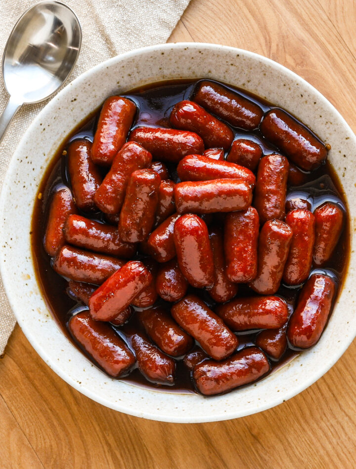 Slow cooker little smokies with grape jelly sauce in a serving bowl.