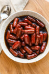 Slow cooker little smokies with grape jelly sauce in a serving bowl.