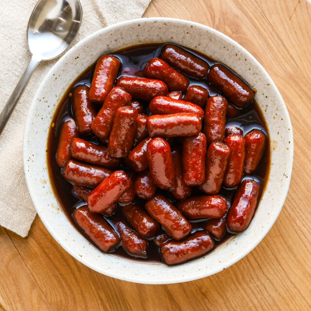 Slow cooker little smokies with grape jelly sauce in a serving bowl.