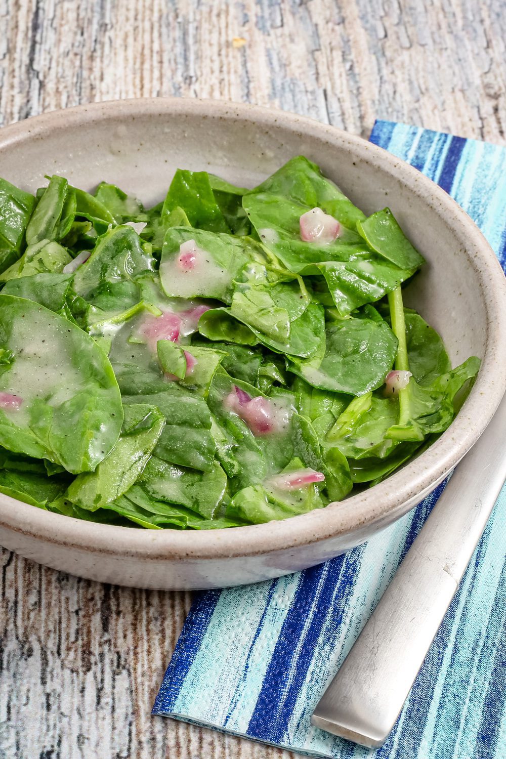 A serving of wilted spinach salad in a bowl