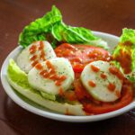 french dressing on a simple cucumber, tomato, and lettuce salad