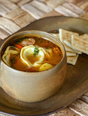 tortellini soup in a cup with crackers