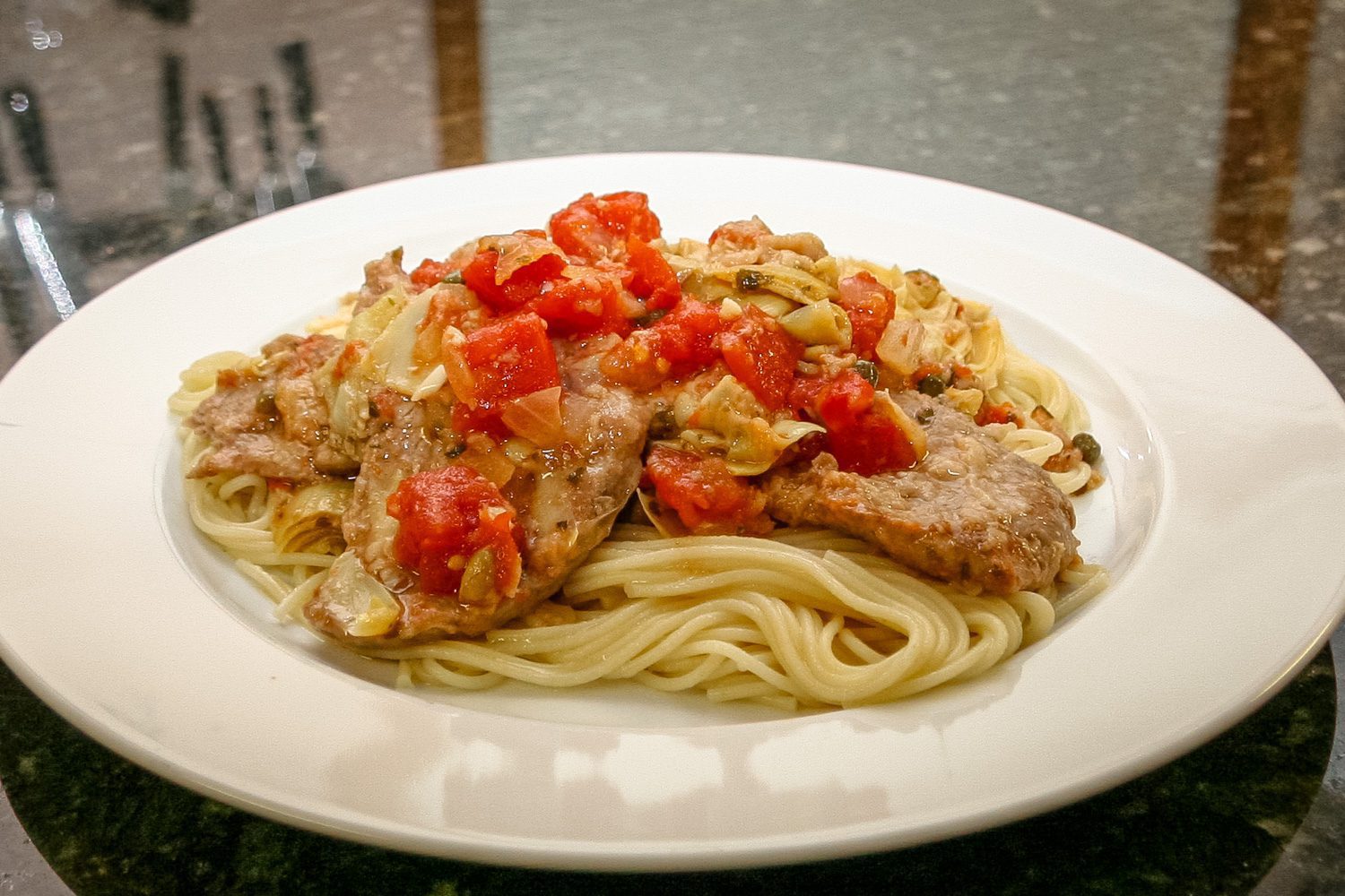 veal cutlets with tomatoes and artichokes on pasta